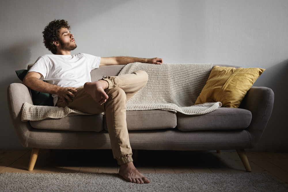 Fotografía de un hombre relajado en un sofá.